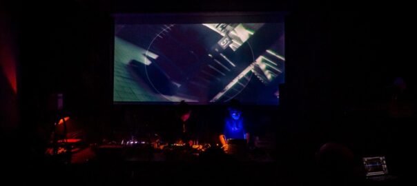 Zwei lachende Musikschaffende mit Kopfhörern im Tonstudio bei warmem Licht